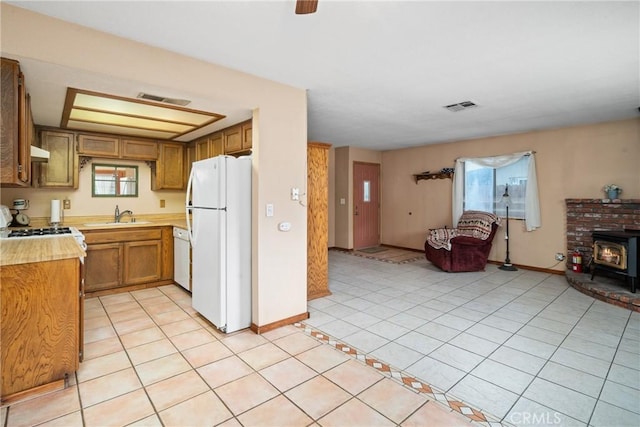 42868 Ranch Club Rd, Lake Elizabeth, CA 93532 - kitchen with white appliances, light countertops, a wood stove, light tile patterned flooring, and baseboards