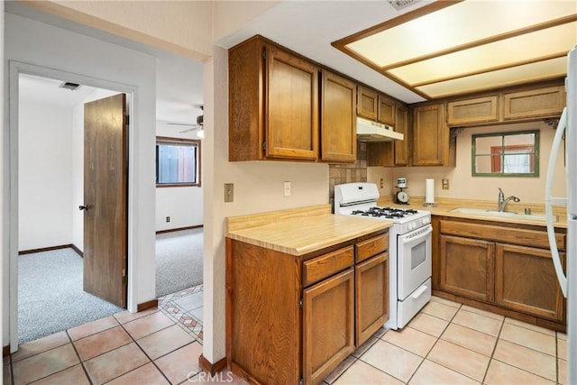42868 Ranch Club Rd, Lake Elizabeth, CA 93532 - kitchen featuring white range with gas cooktop, under cabinet range hood, light colored carpet, brown cabinets, and light countertops