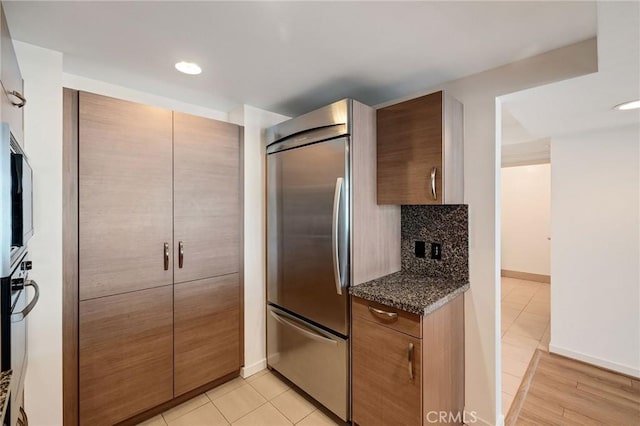 13650 Marina Pointe Dr Unit 908, Marina Del Rey, CA 90292 - kitchen featuring built in fridge, tasteful backsplash, baseboards, light tile patterned floors, and dark stone countertops