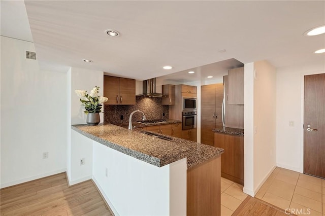13650 Marina Pointe Dr Unit 908, Marina Del Rey, CA 90292 - kitchen featuring wall chimney range hood, oven, built in microwave, brown cabinets, and backsplash
