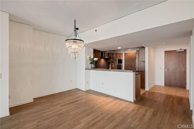 13650 Marina Pointe Dr Unit 908, Marina Del Rey, CA 90292 - kitchen with light wood-type flooring, a chandelier, a peninsula, dark stone counters, and baseboards