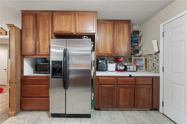 3970 Oakland Ave, Clearlake, CA 95422 - kitchen featuring stainless steel appliances, tile countertops, brown cabinets, backsplash, and a textured ceiling