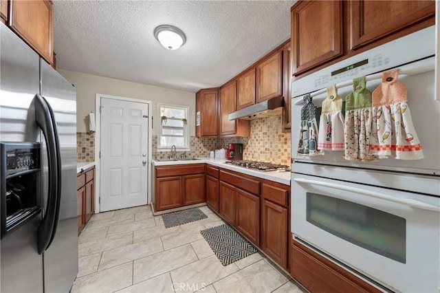 3970 Oakland Ave, Clearlake, CA 95422 - kitchen with stainless steel appliances, light countertops, brown cabinetry, decorative backsplash, and a textured ceiling