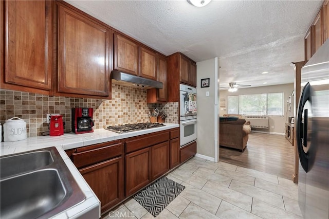 3970 Oakland Ave, Clearlake, CA 95422 - kitchen with freestanding refrigerator, double oven, stainless steel gas stovetop, open floor plan, and brown cabinetry