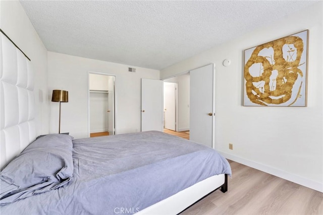 715 Windwood Dr, Walnut, CA 91789 - bedroom featuring light wood-type flooring, a textured ceiling, baseboards, and a walk in closet