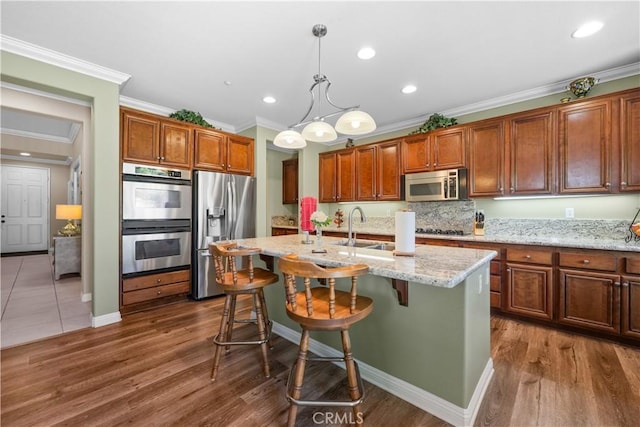 1625 Valley Falls Ave, Redlands, CA 92374 - kitchen with stainless steel appliances, a sink, ornamental molding, a center island with sink, and dark wood-style flooring