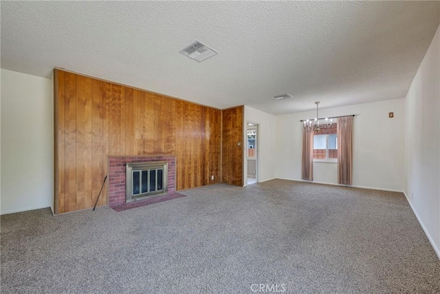 436 W Porter Ave, Fullerton, CA 92832 - unfurnished living room featuring a chandelier, wooden walls, carpet flooring, a brick fireplace, and a textured ceiling