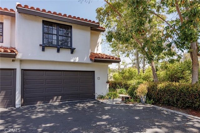 34101 Via California Unit 12, San Juan Capistrano, CA 92675 - mediterranean / spanish-style home with a tile roof, an attached garage, driveway, and stucco siding