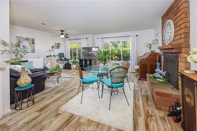 34101 Via California Unit 12, San Juan Capistrano, CA 92675 - dining space featuring light wood finished floors, ceiling fan, and a brick fireplace