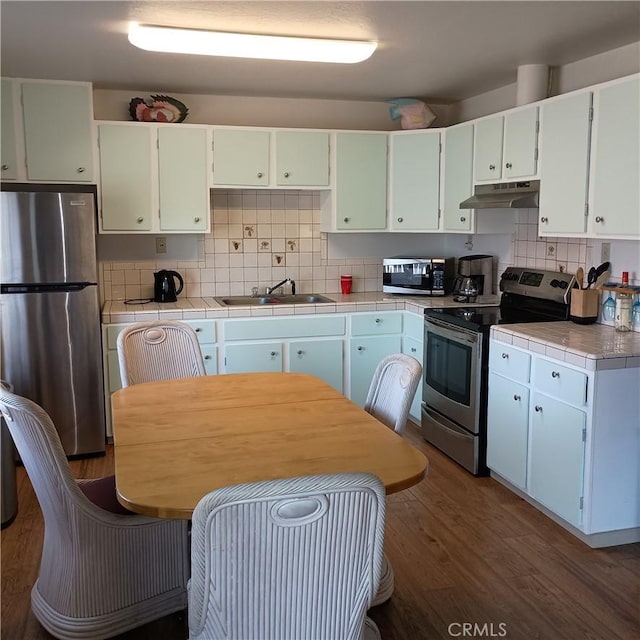 10098 Crestview Dr, Clearlake, CA 95424 - kitchen with appliances with stainless steel finishes, under cabinet range hood, wood finished floors, decorative backsplash, and tile counters