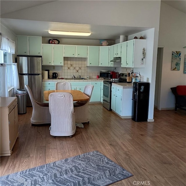 10098 Crestview Dr, Clearlake, CA 95424 - kitchen featuring appliances with stainless steel finishes, tile counters, under cabinet range hood, dark wood-type flooring, and vaulted ceiling