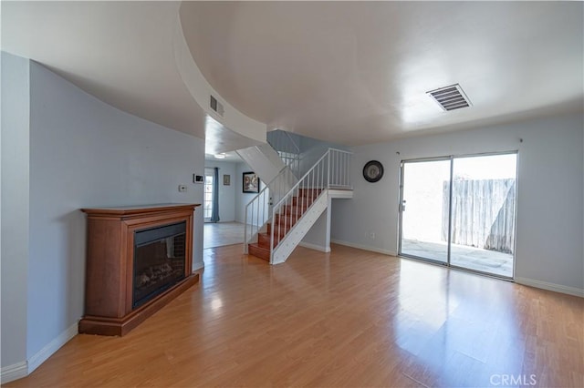 13905 Magnolia St, Garden Grove, CA 92844 - unfurnished living room featuring stairway, light wood-style floors, and a glass covered fireplace