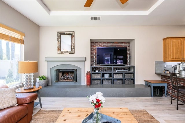 23840 Costa Mesa Way, Murrieta, CA 92562 - living room with a tray ceiling, a fireplace with raised hearth, ceiling fan, and wood finished floors