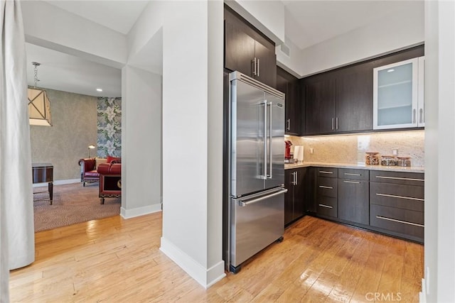 402 Rockefeller Unit 407, Irvine, CA 92612 - kitchen with built in refrigerator, light countertops, light wood finished floors, glass insert cabinets, and tasteful backsplash