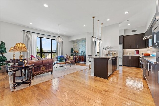 402 Rockefeller Unit 407, Irvine, CA 92612 - kitchen with a breakfast bar area, light wood finished floors, dark brown cabinetry, light countertops, and open floor plan