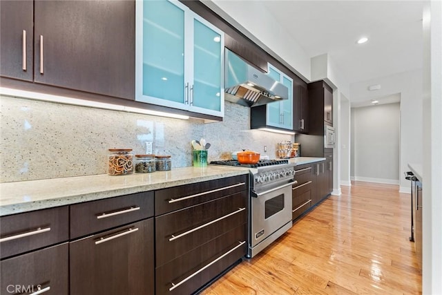 402 Rockefeller Unit 407, Irvine, CA 92612 - kitchen with appliances with stainless steel finishes, dark brown cabinets, under cabinet range hood, light stone countertops, and glass insert cabinets