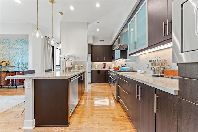 402 Rockefeller Unit 407, Irvine, CA 92612 - kitchen with appliances with stainless steel finishes, a sink, dark brown cabinets, wall chimney exhaust hood, and light wood finished floors