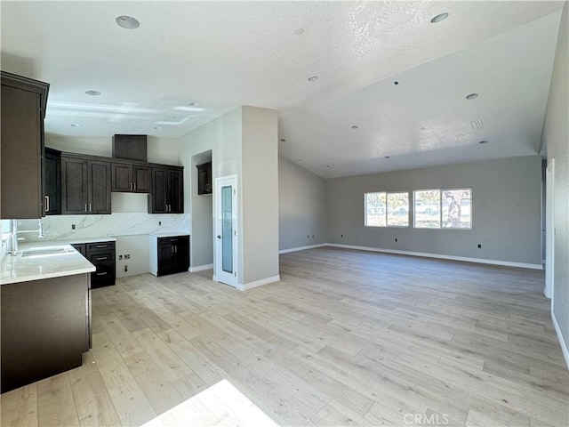 16063 Spruce St, Hesperia, CA 92345 - unfurnished living room featuring a sink, vaulted ceiling, light wood-style flooring, baseboards, and recessed lighting