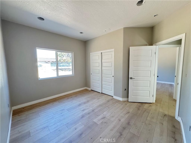 16063 Spruce St, Hesperia, CA 92345 - unfurnished bedroom featuring light wood-style floors, a closet, baseboards, and a textured ceiling