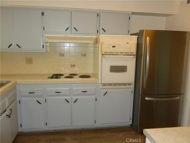 26276 Foxgrove Rd, Menifee, CA 92586 - kitchen with white appliances, decorative backsplash, under cabinet range hood, dark wood-style flooring, and white cabinets