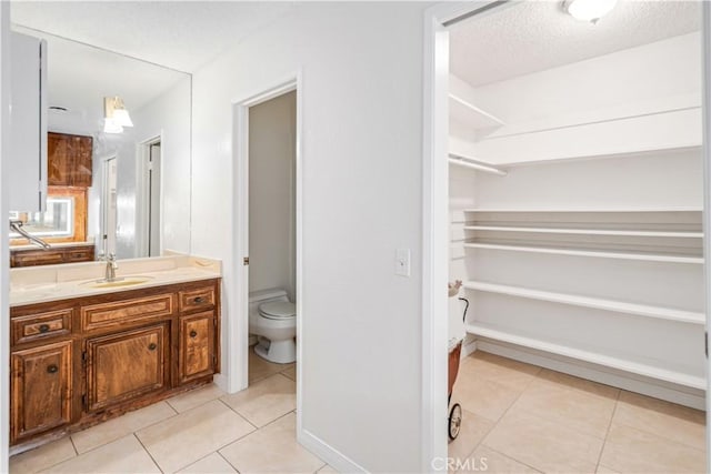 44114 30th St W, Lancaster, CA 93536 - bathroom featuring tile patterned flooring, vanity, toilet, a textured ceiling, and a closet