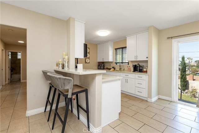 901 S Clymar Ave, Compton, CA 90220 - kitchen with light tile patterned floors, light countertops, white cabinets, and a breakfast bar