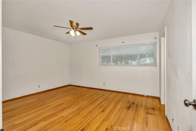 635 Brookdale Dr, Merced, CA 95340 - spare room featuring ceiling fan, light wood-style floors, and baseboards