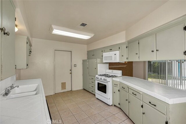 635 Brookdale Dr, Merced, CA 95340 - kitchen with white appliances, tile countertops, a sink, a peninsula, and light tile patterned flooring