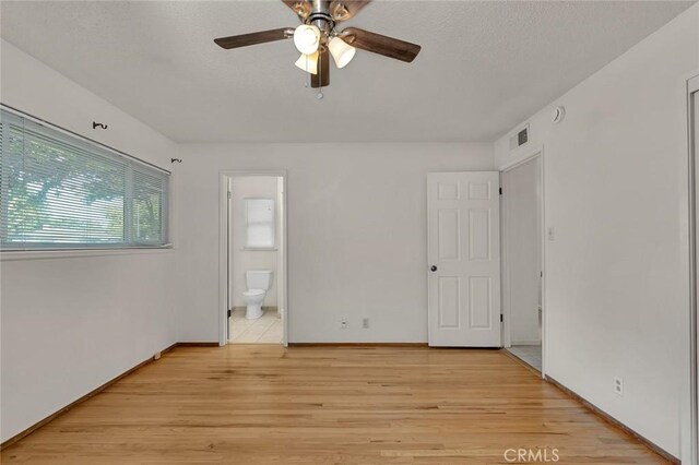635 Brookdale Dr, Merced, CA 95340 - unfurnished bedroom featuring light wood-style floors, ensuite bath, a textured ceiling, a ceiling fan, and baseboards