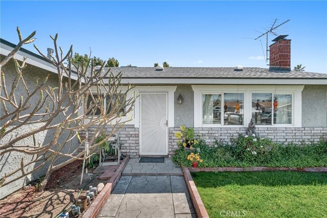 9945 Date St, Fontana, CA 92335 - property entrance with stucco siding, a chimney, a yard, and roof with shingles