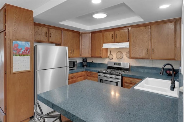 9945 Date St, Fontana, CA 92335 - kitchen with stainless steel appliances, a sink, a raised ceiling, a peninsula, and under cabinet range hood