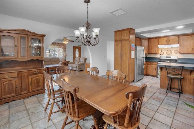 9945 Date St, Fontana, CA 92335 - dining room featuring a chandelier, arched walkways, a ceiling fan, and light stone finish floors