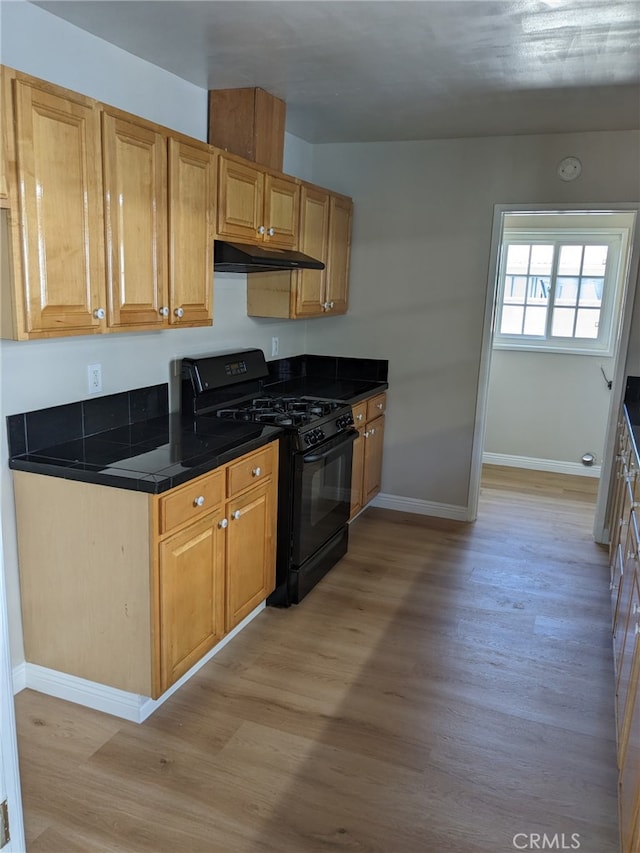 12707 Hoback St, Norwalk, CA 90650 - kitchen featuring black gas range oven, light wood finished floors, under cabinet range hood, and baseboards