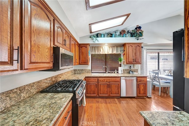 42635 56th St W, Lancaster, CA 93536 - kitchen with stainless steel appliances, a sink, lofted ceiling, a skylight, and light wood-style floors
