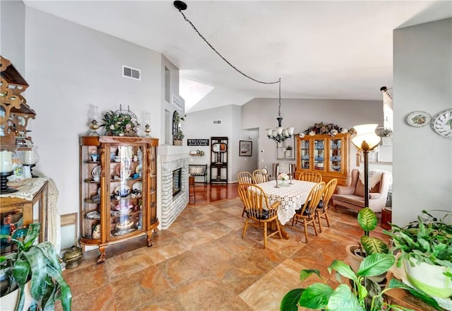 42635 56th St W, Lancaster, CA 93536 - dining room featuring lofted ceiling, a chandelier, a glass covered fireplace, and light stone finish flooring
