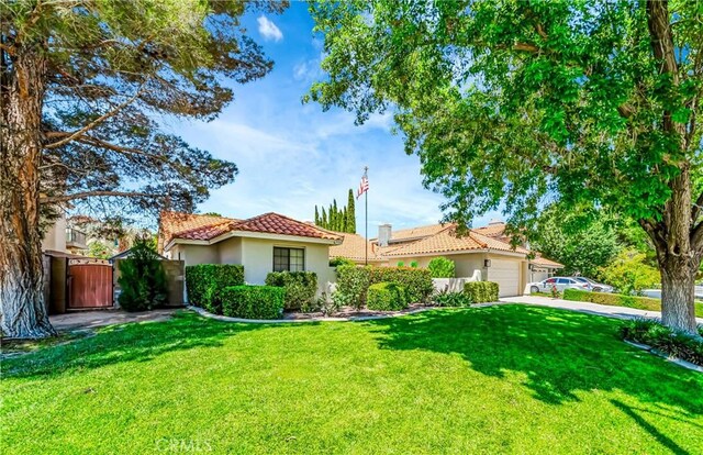 42635 56th St W, Lancaster, CA 93536 - view of front of property with a tile roof, an attached garage, stucco siding, a front lawn, and driveway