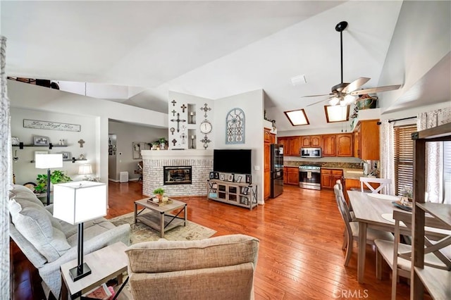 42635 56th St W, Lancaster, CA 93536 - living area featuring vaulted ceiling, ceiling fan, light wood-style floors, and a brick fireplace