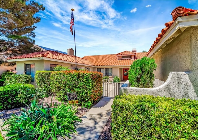 42635 56th St W, Lancaster, CA 93536 - view of front facade with stucco siding, a gate, a tile roof, and a chimney