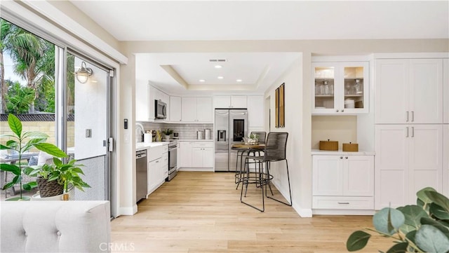 15061 Glass Cir, Irvine, CA 92604 - kitchen with stainless steel appliances, light countertops, light wood-style floors, a raised ceiling, and white cabinetry