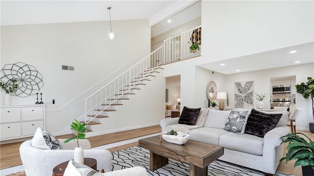 15061 Glass Cir, Irvine, CA 92604 - living area featuring stairs, light wood-type flooring, a towering ceiling, recessed lighting, and baseboards