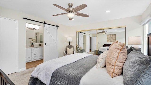 15061 Glass Cir, Irvine, CA 92604 - bedroom with a barn door, light colored carpet, recessed lighting, a ceiling fan, and connected bathroom