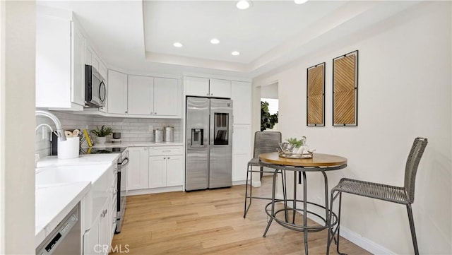 15061 Glass Cir, Irvine, CA 92604 - kitchen featuring stainless steel appliances, light wood finished floors, decorative backsplash, white cabinets, and recessed lighting