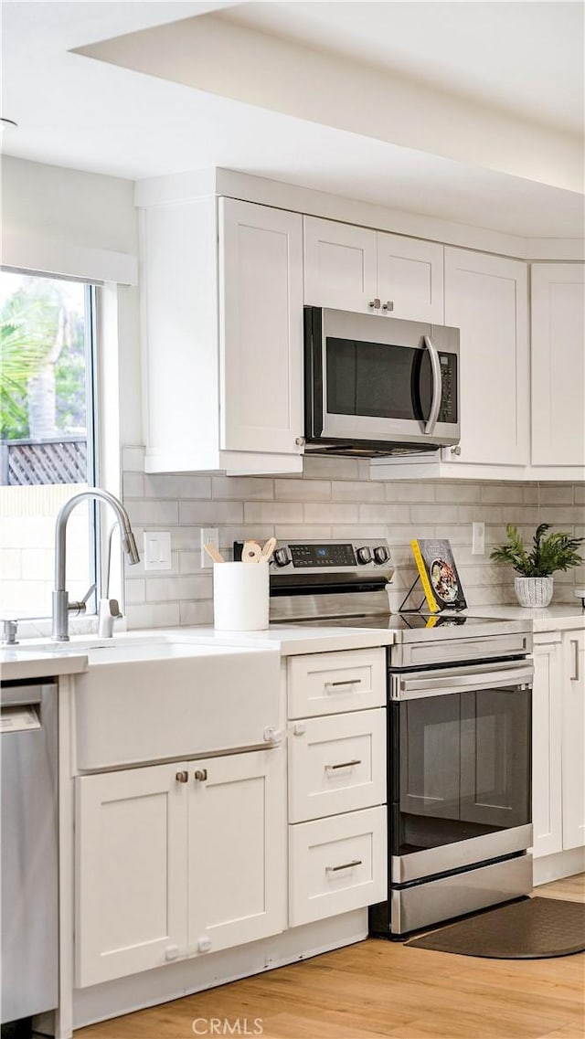 15061 Glass Cir, Irvine, CA 92604 - kitchen with appliances with stainless steel finishes, light countertops, white cabinetry, and backsplash