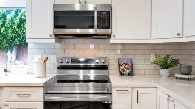 15061 Glass Cir, Irvine, CA 92604 - kitchen with appliances with stainless steel finishes, white cabinets, decorative backsplash, and light stone counters