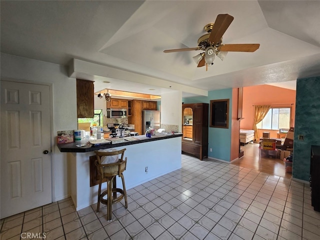 983 Oak St, Costa Mesa, CA 92627 - kitchen featuring appliances with stainless steel finishes, a peninsula, dark countertops, a ceiling fan, and brown cabinetry