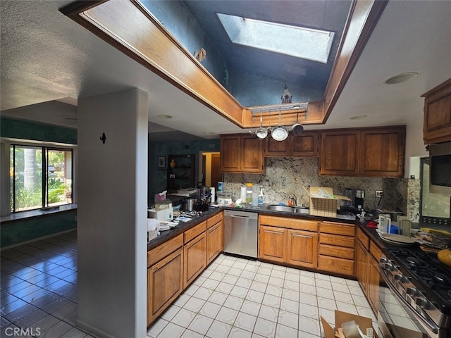 983 Oak St, Costa Mesa, CA 92627 - kitchen featuring stainless steel appliances, dark countertops, decorative backsplash, a sink, and light tile patterned floors