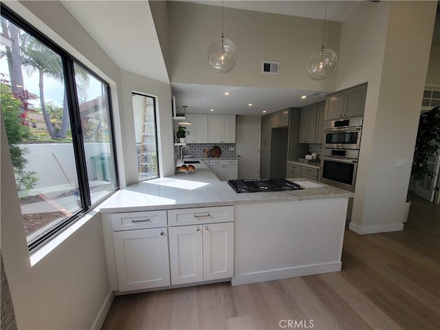 2722 Olympia Dr, Carlsbad, CA 92010 - kitchen featuring gas cooktop, double oven, light wood-style floors, light stone countertops, and high vaulted ceiling