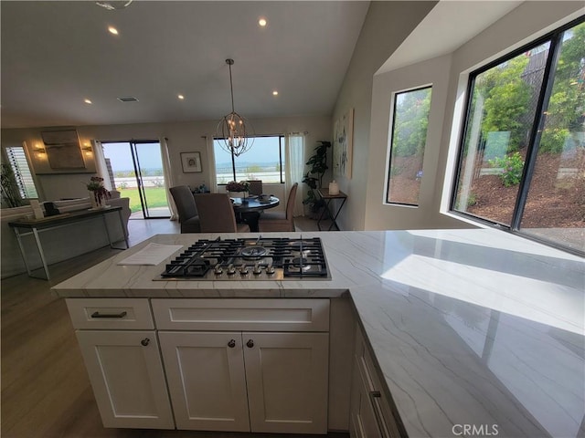 2722 Olympia Dr, Carlsbad, CA 92010 - kitchen with stainless steel gas stovetop, white cabinets, light stone counters, open floor plan, and recessed lighting
