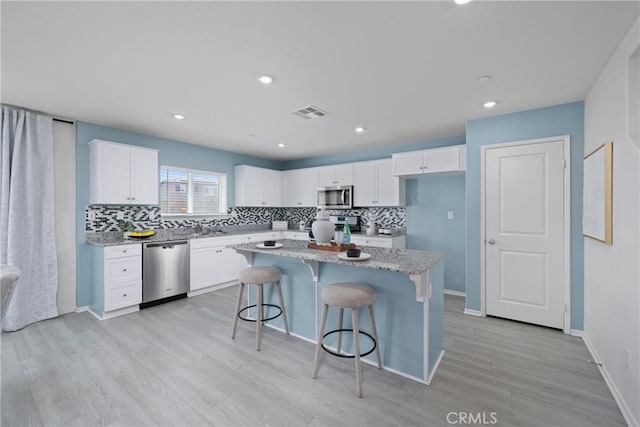 1330 Carolina Ct, Hemet, CA 92543 - kitchen featuring stainless steel appliances, decorative backsplash, a kitchen breakfast bar, white cabinetry, and recessed lighting
