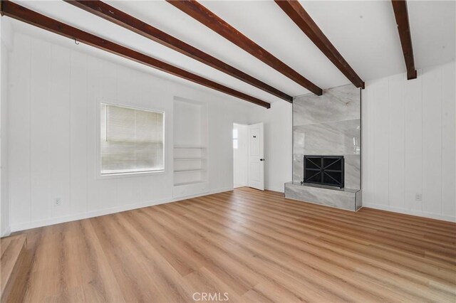 611 S Thorson Ave, Compton, CA 90221 - unfurnished living room with beamed ceiling, light wood finished floors, a premium fireplace, built in shelves, and baseboards